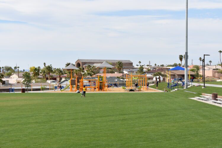 grassy field with Cypress Park playground in the distance