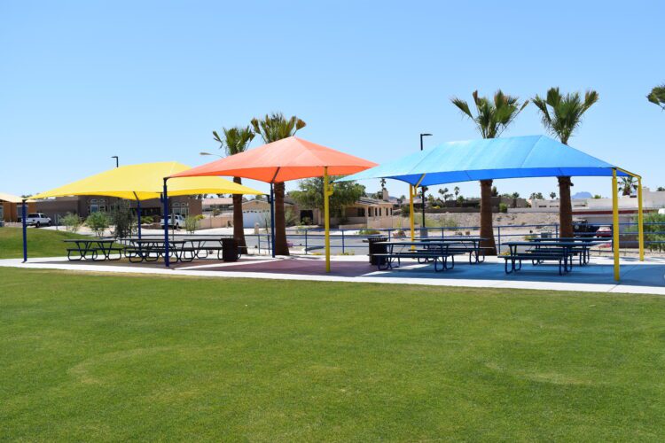 yellow, orange and blue sun shades over picnic benches