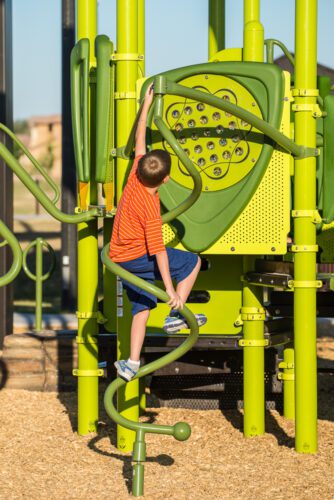 boy climbing up playground pole