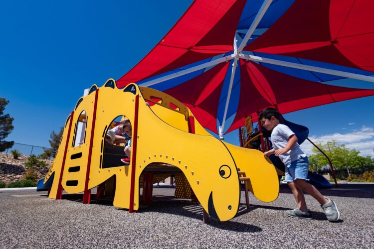 dinosaur playground structure beneath sun shade