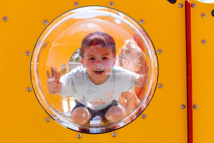 child looking through bubble in playground equipment