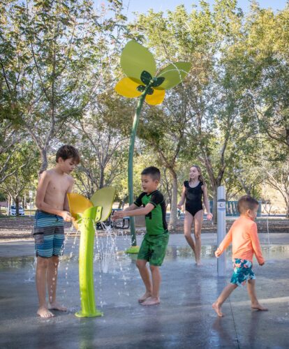 kids playing with spray splash pad equipment