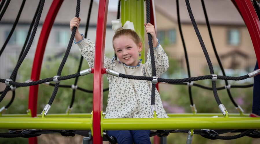 girl hanging on to playground net