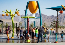 kids playing under large aquatic splash pad equipment