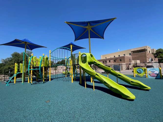 slides and climbing equipment underneath shades at park